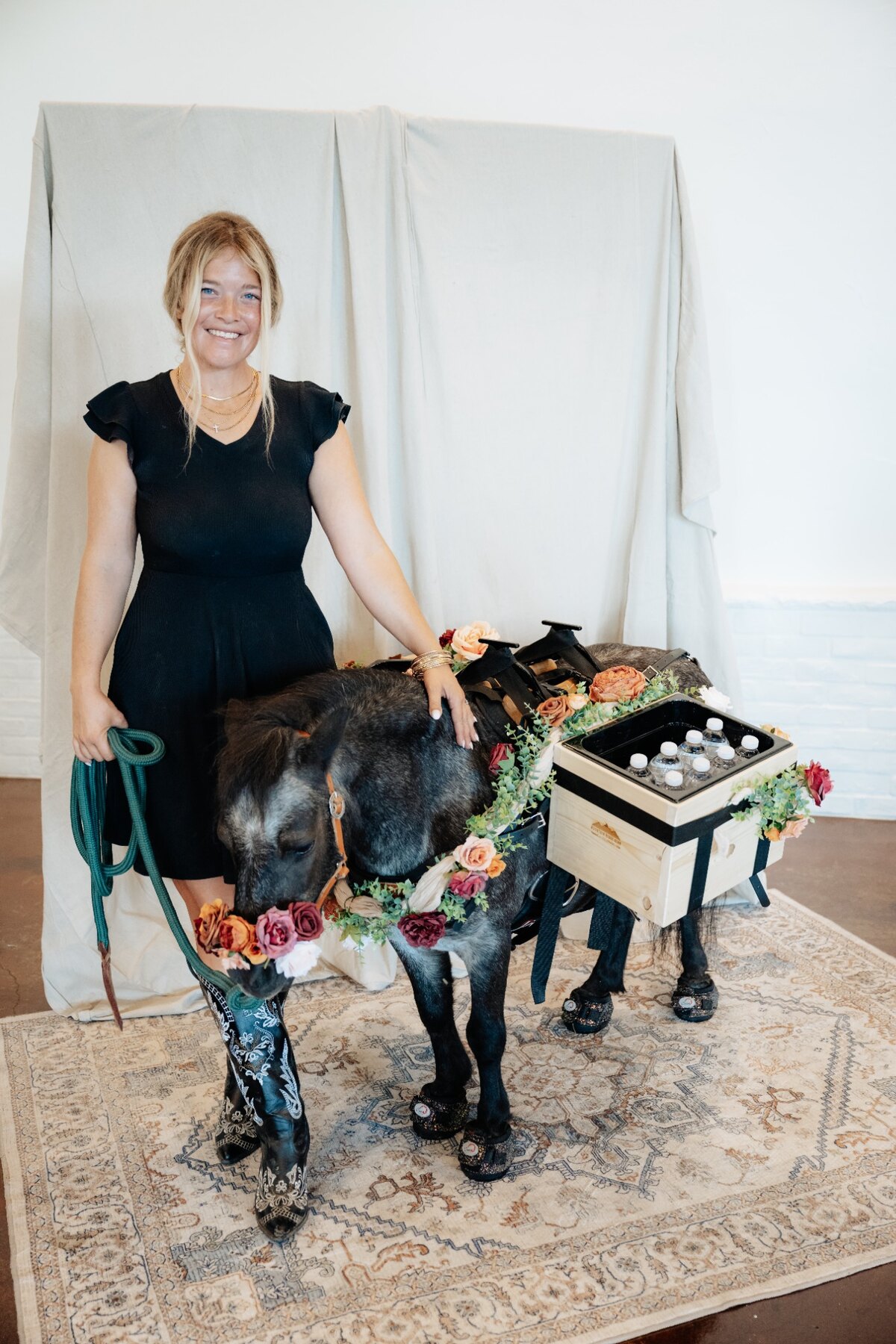 Pickles with his handler, wearing custom florals and carrying bottled drinks at an event